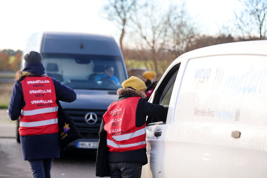 Menschen in roten Warnwesten, die mit Fahrern in Autos sprechen 