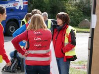 Mehrere Personen, mit Westen bekleidet, im Gespräch vor einem Gebäude