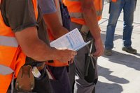 Bauarbeiter mit Warnweste hält einen Infoflyer in der Hand